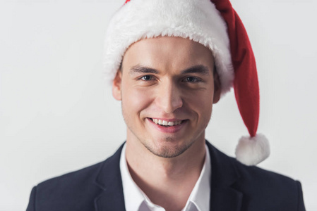英俊的家伙西装和圣诞老人的帽子是看着相机和微笑, 孤立的白色