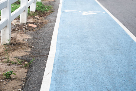 白色自行车标志或图标在蓝色自行车车道与白色篱芭在路边保护人在公园散步