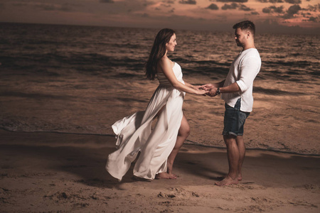 迷人的浪漫年轻夫妇在沙质热带海滩在美丽的日落