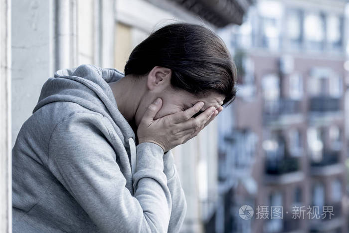 忧郁的女人站在阳台上双手掩着脸哭泣