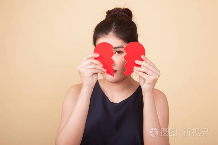 美丽的年轻亚洲女人在米色背景下心碎