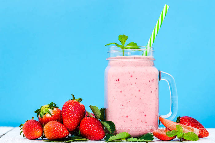 水果奶昔与草莓冰壶的甜点草莓混合在罐子蓝色背景