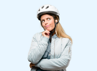 自行车头盔和耳机的年轻女子思考和寻找表达怀疑和疑惑