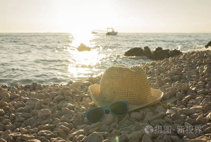 在卵石海滩上的帽子和太阳镜懒洋洋的全景视图