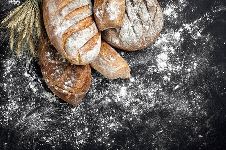 自制黑麦面包洒面粉和各种谷物和种子在黑色的背景与小穗小麦或黑麦和燕麦