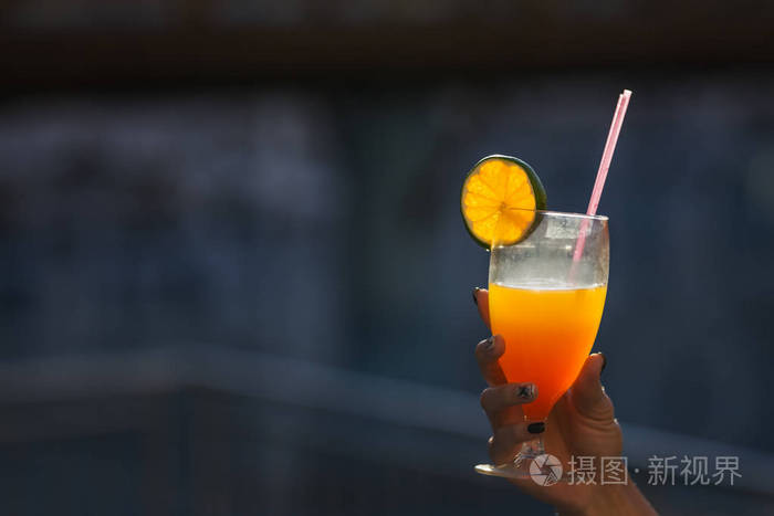 在户外玻璃手拿着一个橙色的鸡尾酒