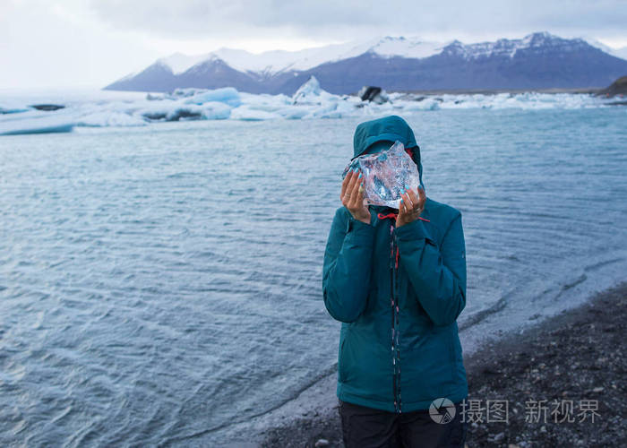 旅游女孩手里拿着一块冰块.它站在冰川上, 靠近冰山