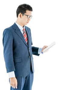 年轻的亚洲商人穿西装戴眼镜, 在白色背景下手持笔记本电脑