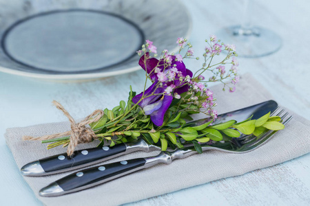 质朴的餐桌设置与紫色的花朵在轻木桌上。在普罗旺斯风格的节日装饰。浪漫晚餐