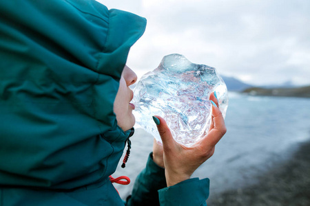 旅游女孩手里拿着一块冰块。它站在冰川上, 靠近冰山