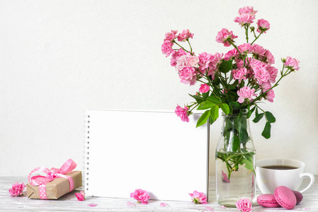 美丽的粉红色玫瑰花花束, 咖啡杯, 杏仁, 礼品盒和空白白色贺卡与地方的文本。节日或婚礼背景。模仿。静物