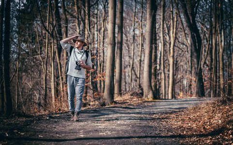旅游男子与老式相机和背包漫步在秋季森林