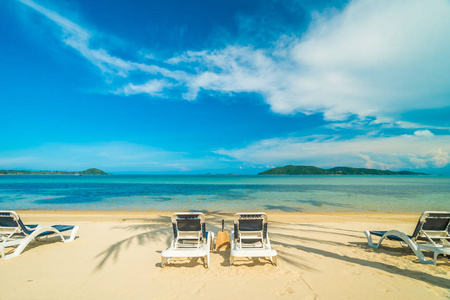 美丽的热带海滩和海与椰子棕榈树和椅子在天堂海岛