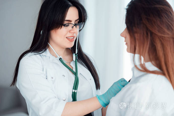 年轻妇女在家庭医生专家检查女性患者用听诊器