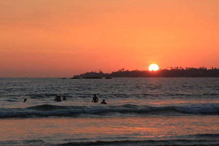 日落在 Weligama 湾海滩与剪影人在海, 斯里兰卡