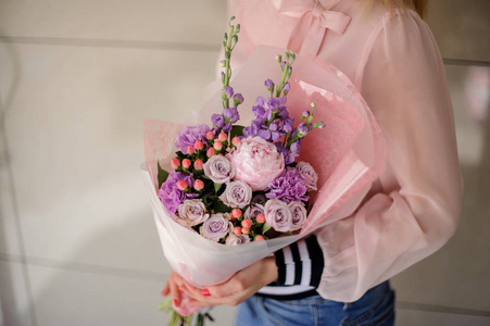 穿着粉红色衬衣的女孩手里拿着一束鲜艳的紫罗兰和粉红色的嫩花照片