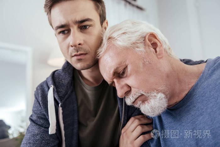 不公平的生活体贴的男人拥抱老人谁睡觉