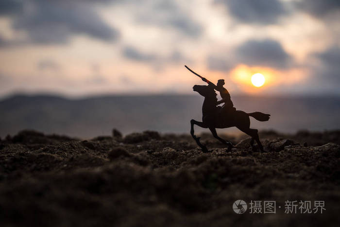 (或勇士) 骑手骑着一把剑准备战斗, 士兵们在黑暗的雾色调的夕阳背景