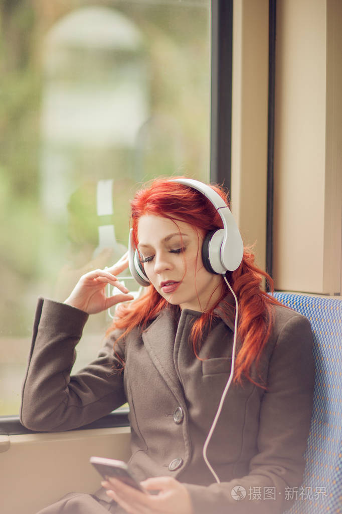 听音乐的年轻美丽的妇女在火车, 地铁, 都市心情概念