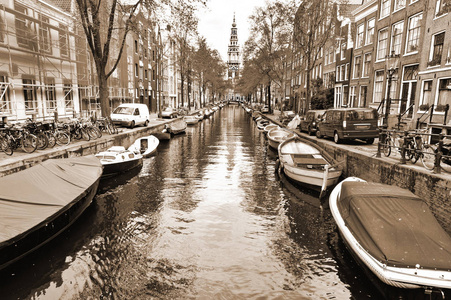 城市场面在阿姆斯特丹与小船和许多自行车。街道看法与自行车停放在一个路堤在阿姆斯特丹的历史中心在荷兰。复古风格棕褐色照片