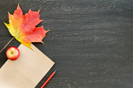 秋天的枫叶 苹果 文本和铅笔在木制的黑色背景上用纸。头顶上的副本空间背景，平坦的顶视图