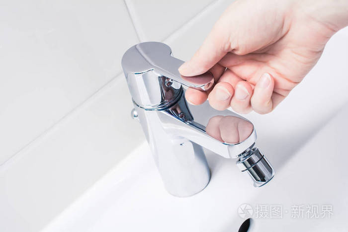 女性手上的铬水龙头手柄准备打开水