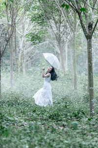 美丽的女人浪漫在白色礼服站立在树橡胶庭院在夏天雨