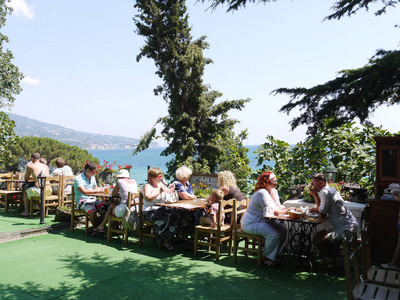 游客们来到海边的咖啡馆, 四周绿树成荫, 俯瞰着大海海边的青山和万里无云的蓝天。休息地点, 旅行
