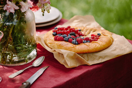 花园桌上有覆盆子葡萄干和蓝莓的开胃馅饼