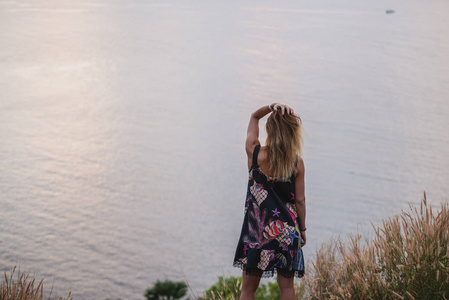 快乐的女人在短礼服享受在海日落。在背景无尽的海洋表面, 复古色彩