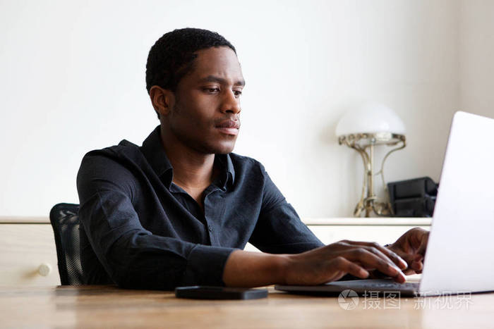 年轻的非洲裔美国人的肖像在笔记本电脑在家工作
