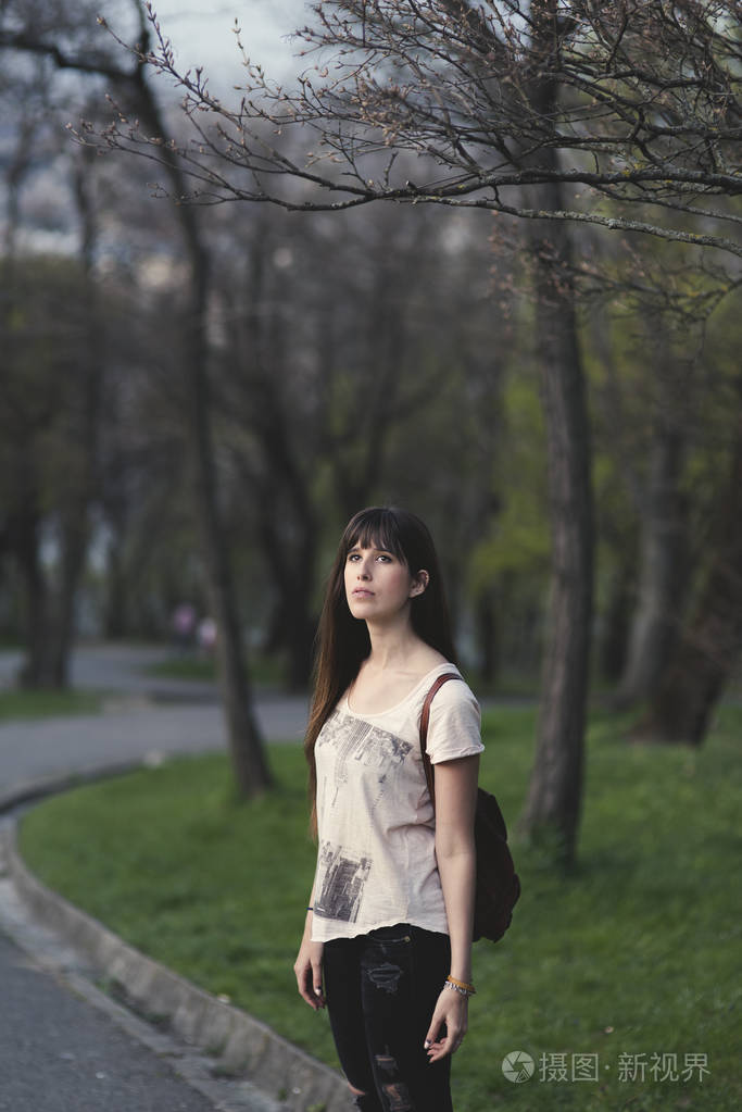 有魅力的年轻女子在公园里享受时光。白人女孩, 长棕色头发, 在一个宁静的姿势