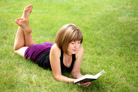 年轻漂亮的女孩在公园里阅读