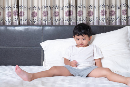 3岁的小可爱的亚洲男孩在家里的床上, 孩子躺在玩, 微笑着在白色的床上枕头和毯子, 与复制空间添加文本