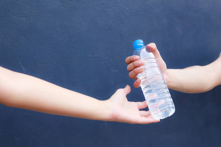 男子手清洁塑料瓶充满新鲜饮用水的妇女在孤立的背景下