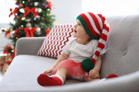 可爱的婴孩在圣诞节服装在家庭沙发上