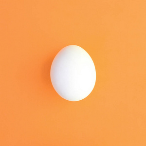 一个白色的复活节彩蛋在一个明亮的橙色背景