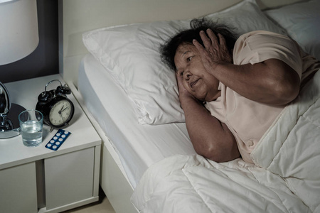 患有失眠症的老妇人晚上睡在床上。