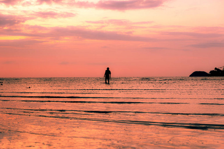 日落时分独自漫步在热带海滩上的男孩剪影