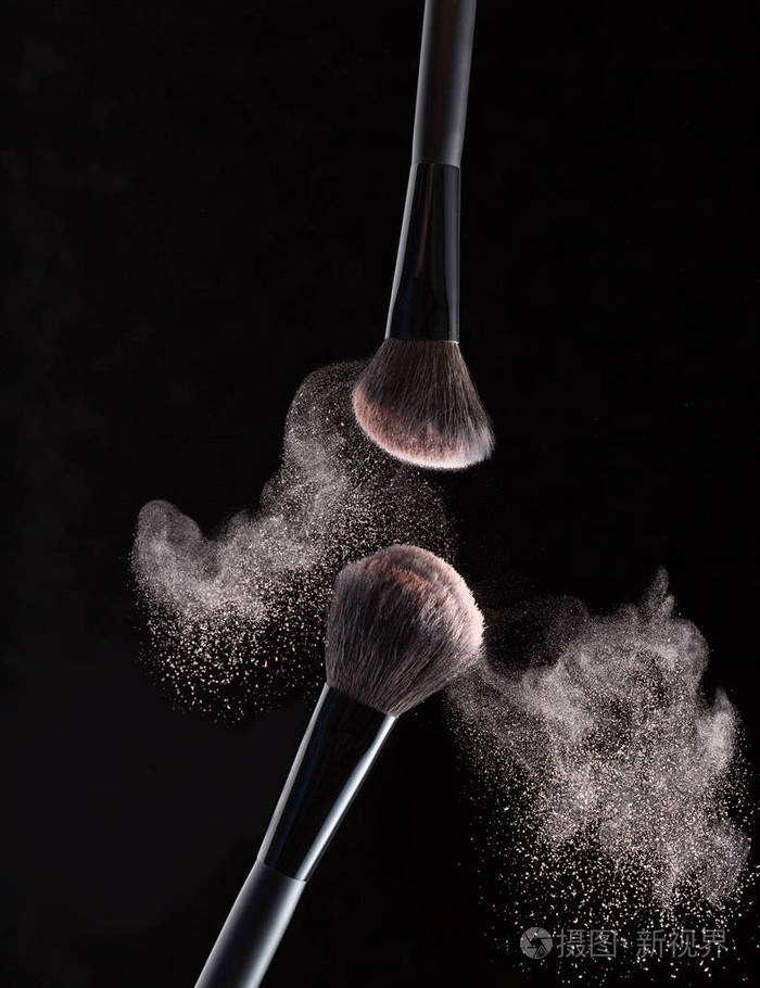 在黑色背景下, 在粉末周围飞行的化妆刷被隔离