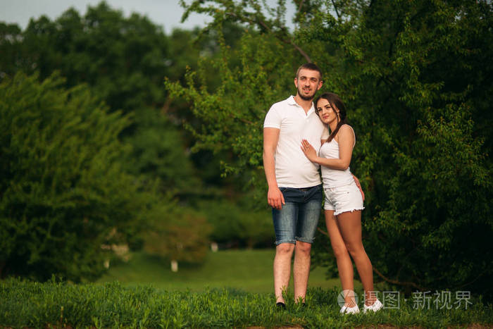 在公园约会.爱的情侣站在草地上, 靠近湖边.浪漫与爱情