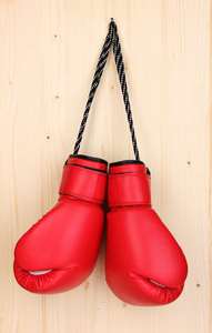 木制背景上挂着的红色拳击手套