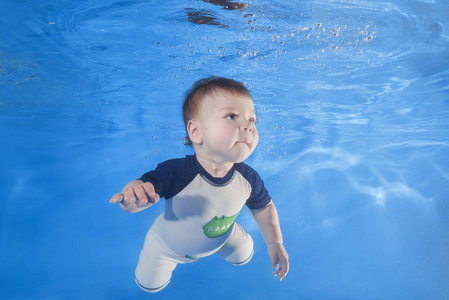 5月男孩在水下游泳在水池里