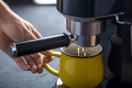 浓咖啡的准备。黑咖啡从机器里倒进了黄色的杯子。专业咖啡酿造在家