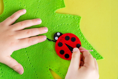 儿童制作毛毡软玩具的绿叶和红色 ladybag。儿童 Diy 活动。特写。儿童工艺品概念