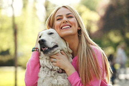 年轻的金发女郎是放松在公园里与她的猎犬