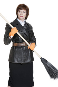 穿着黑色皮革复古夹克的年轻女子, 带上一条士兵的腰带, 在白色的背景上拿着一把木制的扫帚。