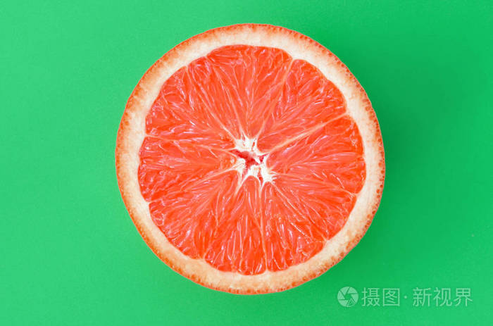 在明亮的背景绿色的一个柚子切片的最高视图。饱和柑橘纹理图像