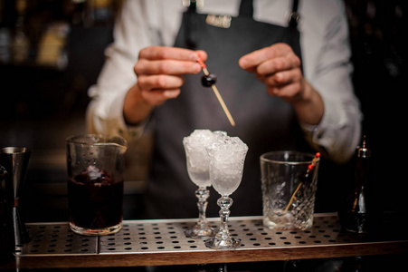 布拉曼装饰两个优雅的鸡尾酒眼镜, 里面装满了冰和樱桃在酒吧柜台上