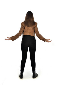 全长肖像的黑发女孩穿着皮夹克和纯黑色衣服。站立的姿态, 被隔绝在白色演播室背景